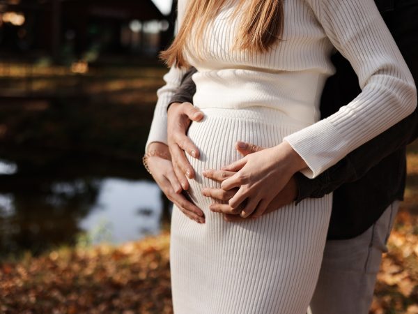 Family day. Stylish unrecognisable marriage pregnant couple waiting for baby. Man is hugging and